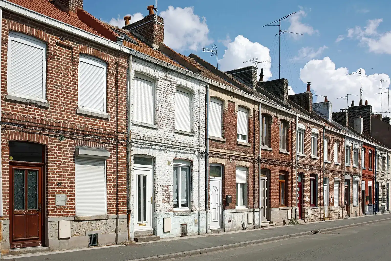 Rangée de maisons ouvrières en brique rouge et blanche, avec portes et fenêtres alignées, dans une rue de Lille