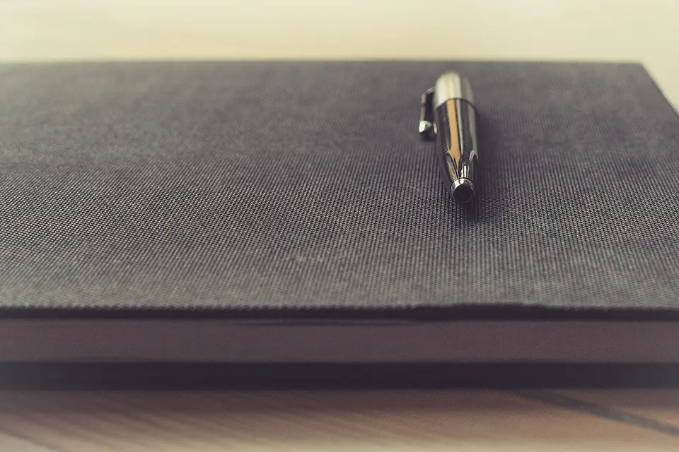 Stylo posé sur un carnet ouvert aux pages blanches